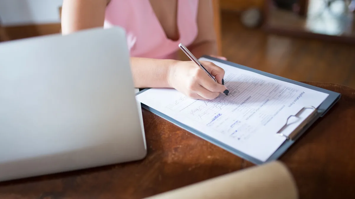 Mujer escribiendo sobre un documento en una mesa de trabajo