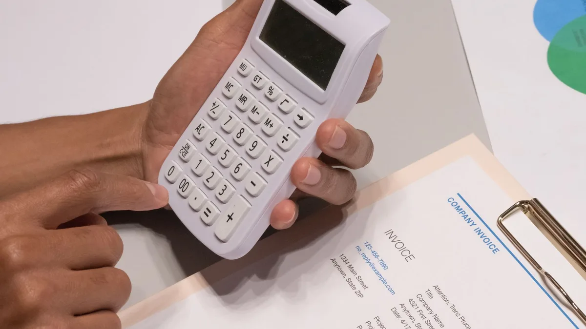 Primer plano de una persona usando una calculadora sobre una mesa de trabajo
