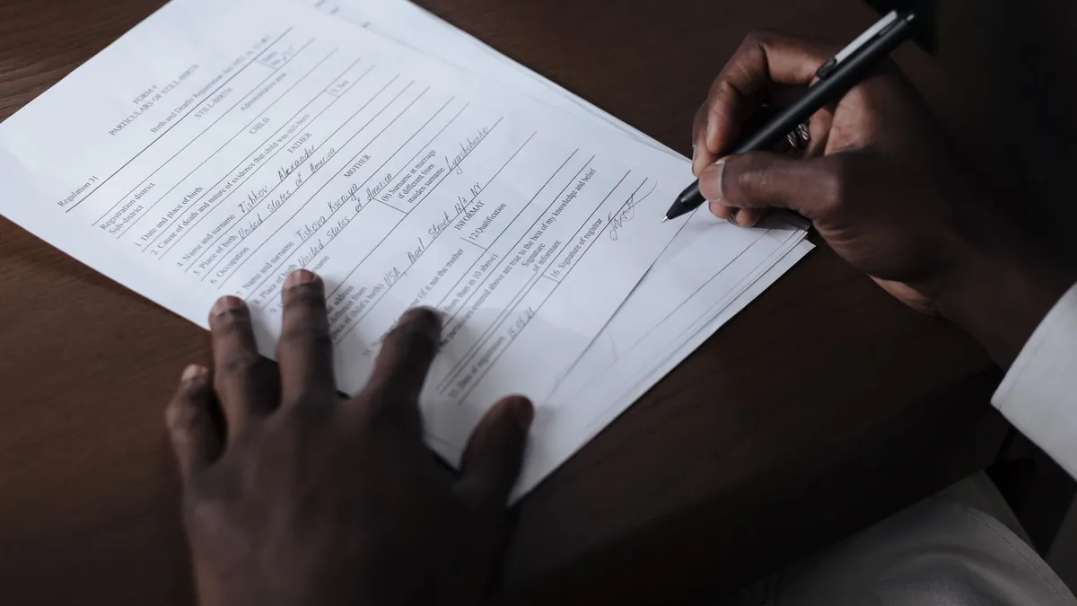 Persona firmando un documento con un bolígrafo sobre una mesa
