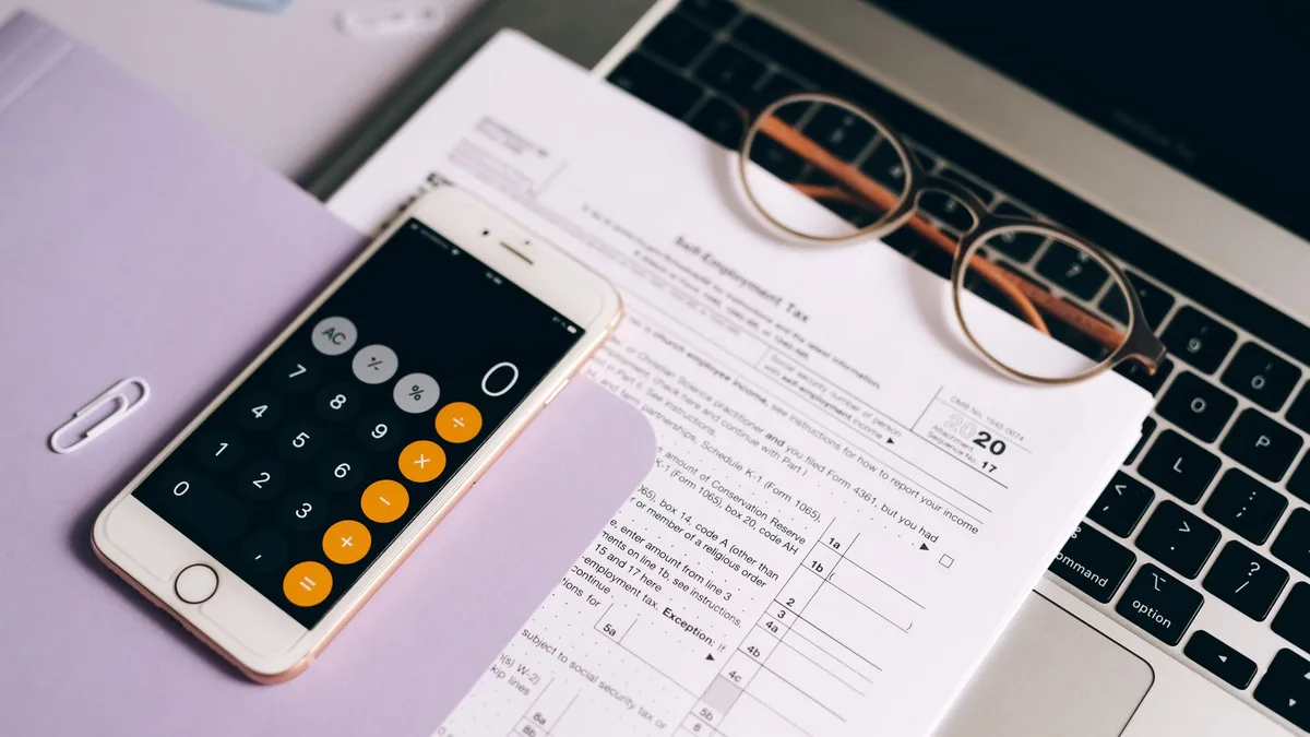 Teléfono móvil con la aplicación de calculadora sobre un documento de impuestos
