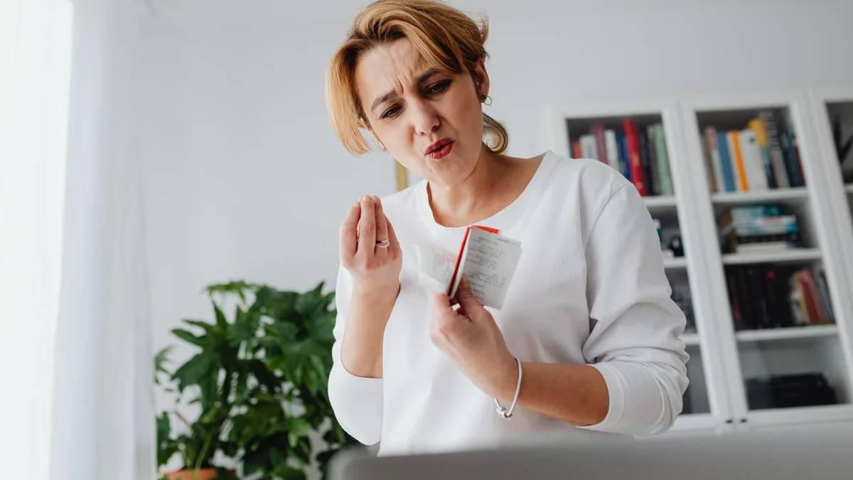 Mujer con gesto de preocupación sosteniendo un montón de tickets y facturas