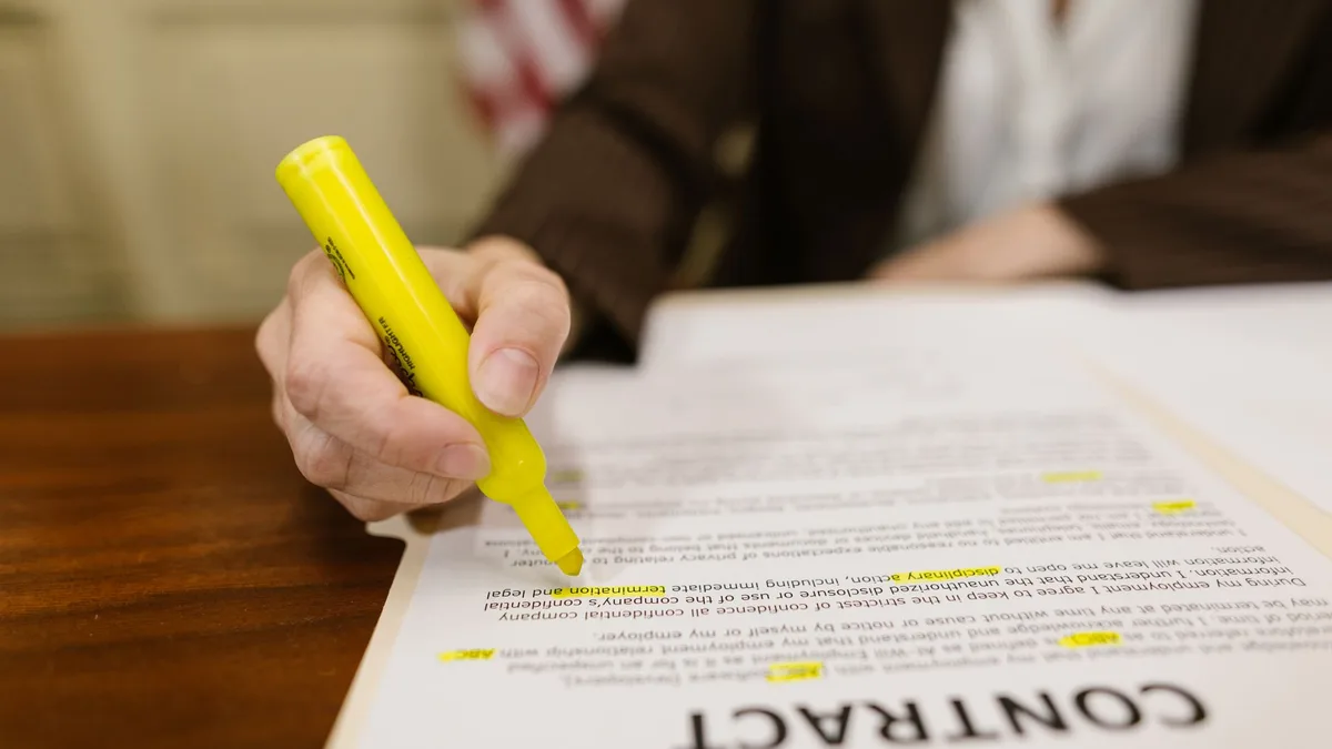 Primer plano de una persona escribiendo sobre un contrato impreso